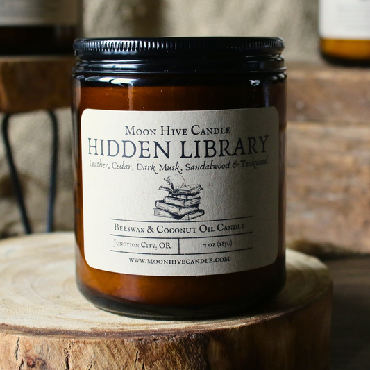 Moon Hive Candle labeled 'Hidden Library' on a wooden surface