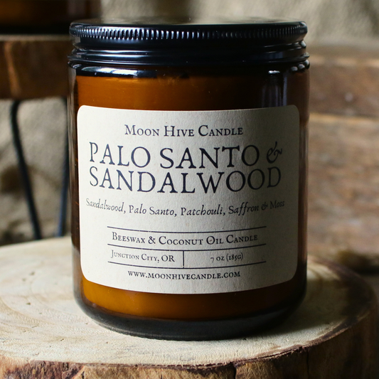 Palo Santo & Sandalwood candle jar with label on a wooden surface